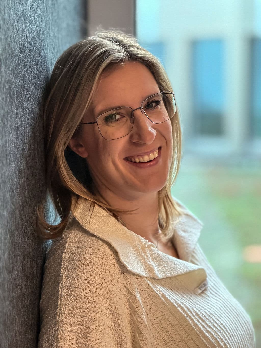 Carolin, Coach für hochsensible Menschen, lehnt lächelnd an einer Wand